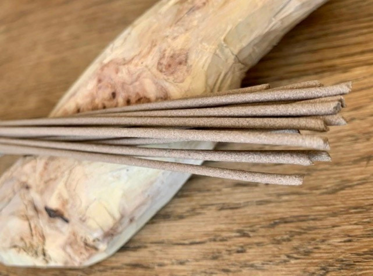 Hand made artisan sandalwood incense sticks resting on a log of sandalwood
