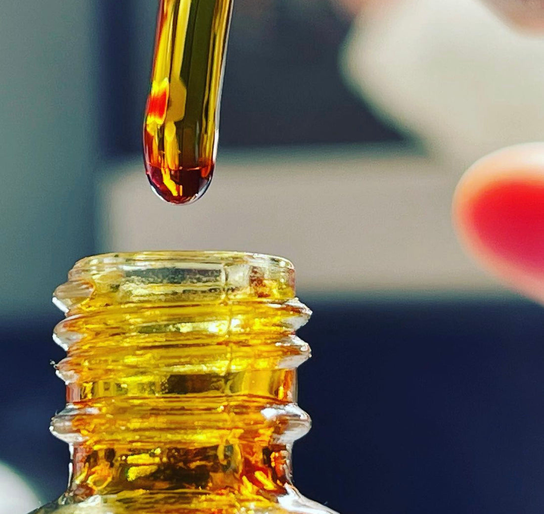 Close up of a man holding a pipette with Oud oil dripping off into a bottle with blurred background 