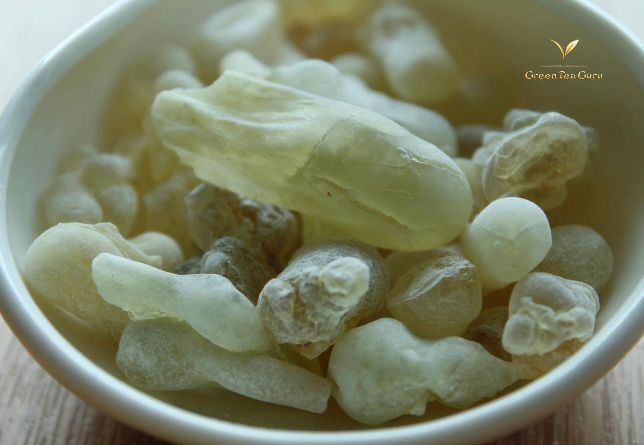 Omani royal green frankincense pieces in a cup with wooden table in background 