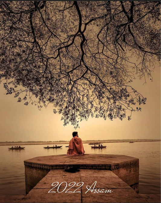 Picture of a Buddhist monk meditating by a lake under a tree