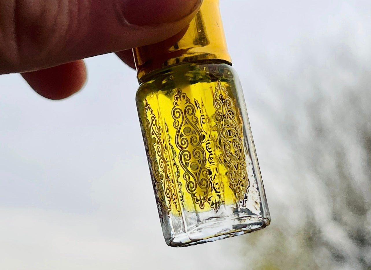 A man holding an Attar bottle of Java Indonesian patchouli oil to the sky