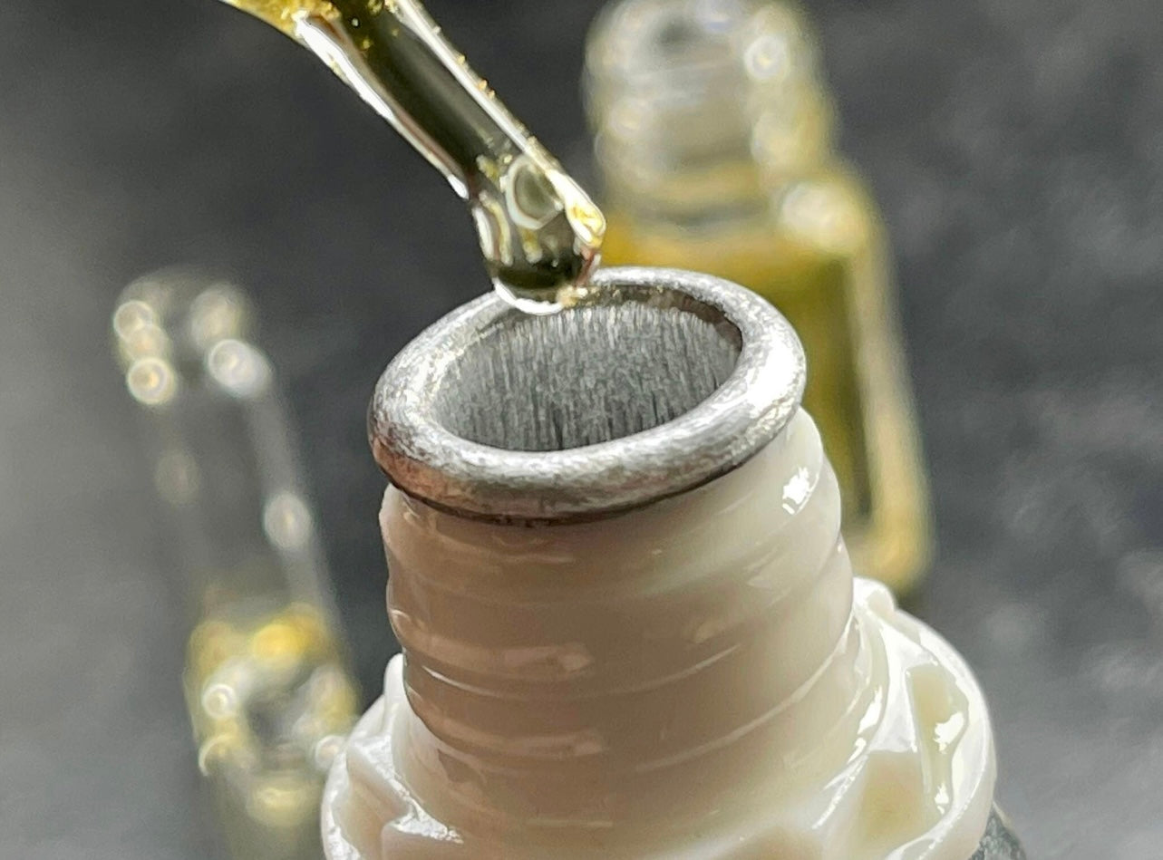 Man using a pipette taking a Sandalwood essential oil from a bottle on the table