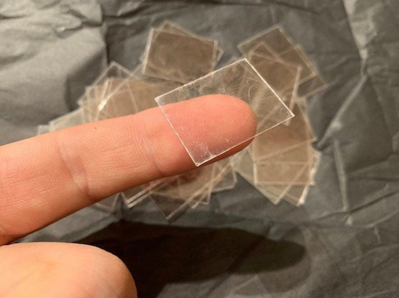 Man holding a mica sheet on his finger with Mica sheets in the background