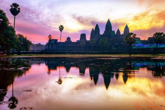 A picture showing Cambodian religious building next to a lake at sunset
