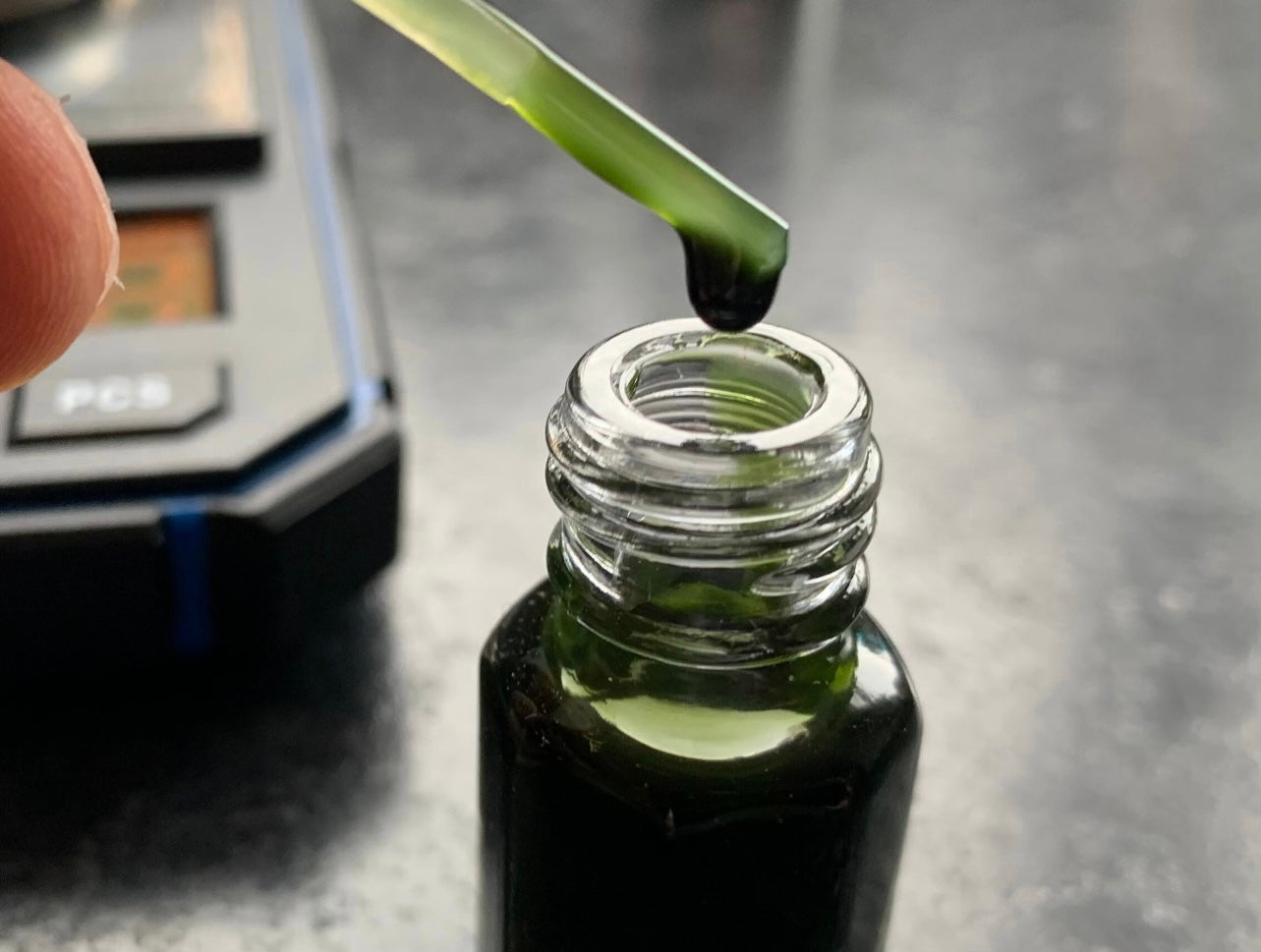 A picture of a man taking a pipette out of a bottle of Indian vetiver Ruh Khus essential oil