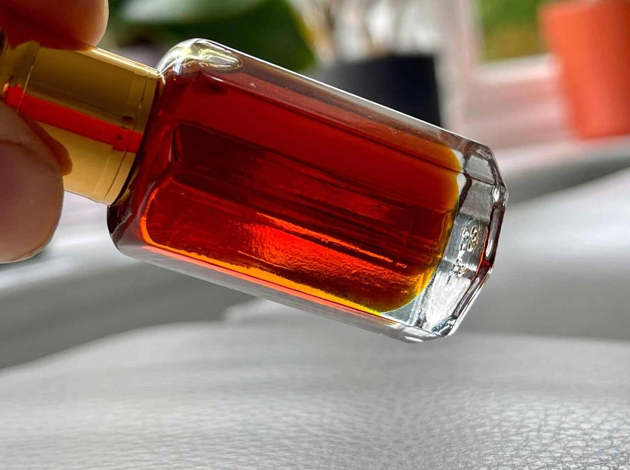 Man holding a bottle of Indian Oud on a sofa