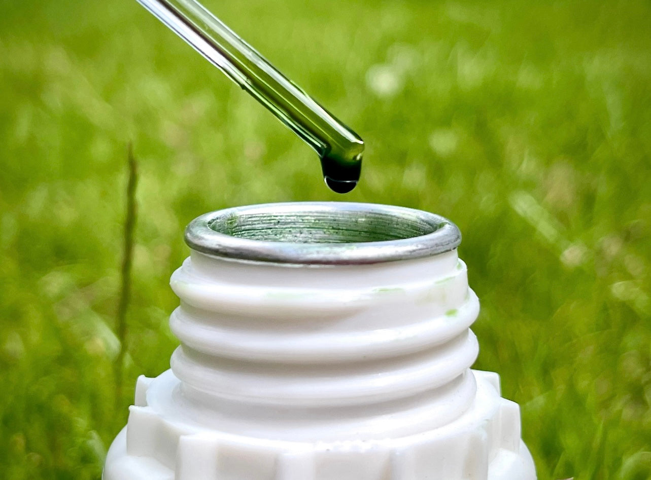 A man taking a pipette out of a large bottle of vetiver essential oil