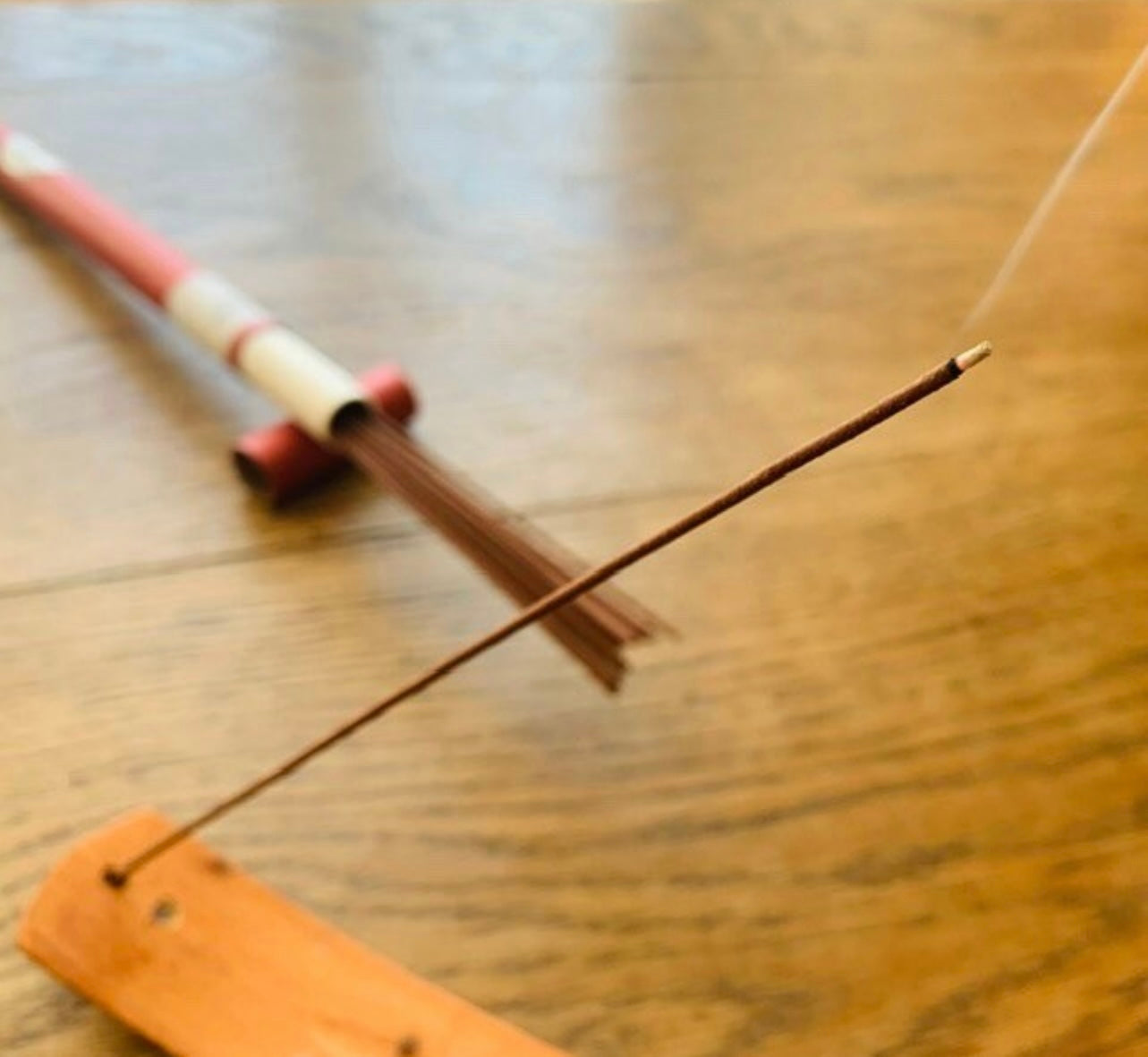 A Hainan Rosewood incense stick, burning in an incense holder on a table