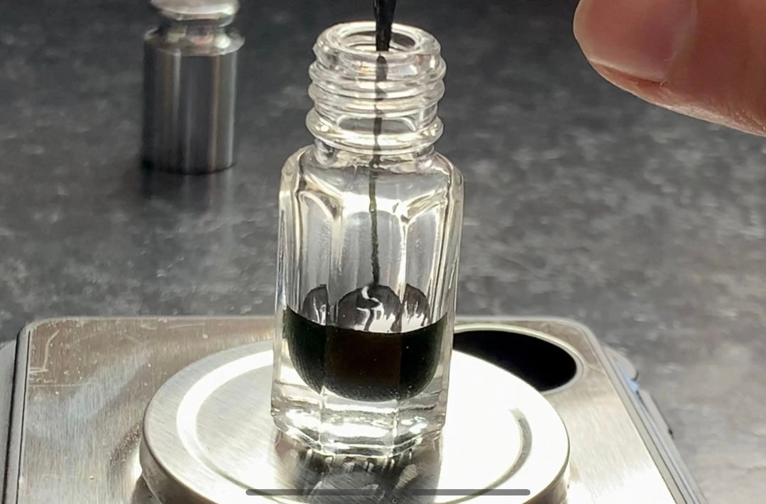 A man pouring Indian vetiver Ruh Khus essential oil into an Attar bottle